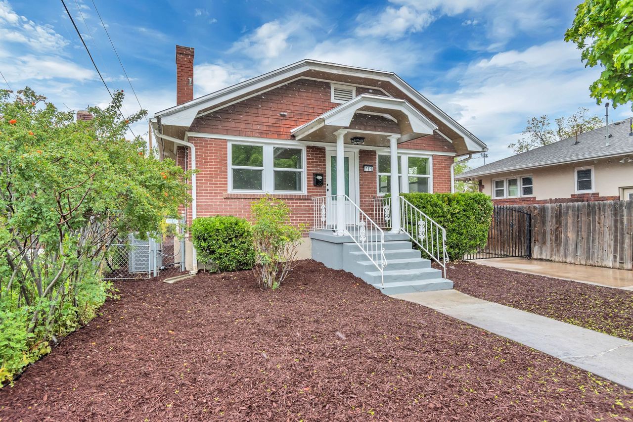 Bungalow featuring a chimney and brick siding