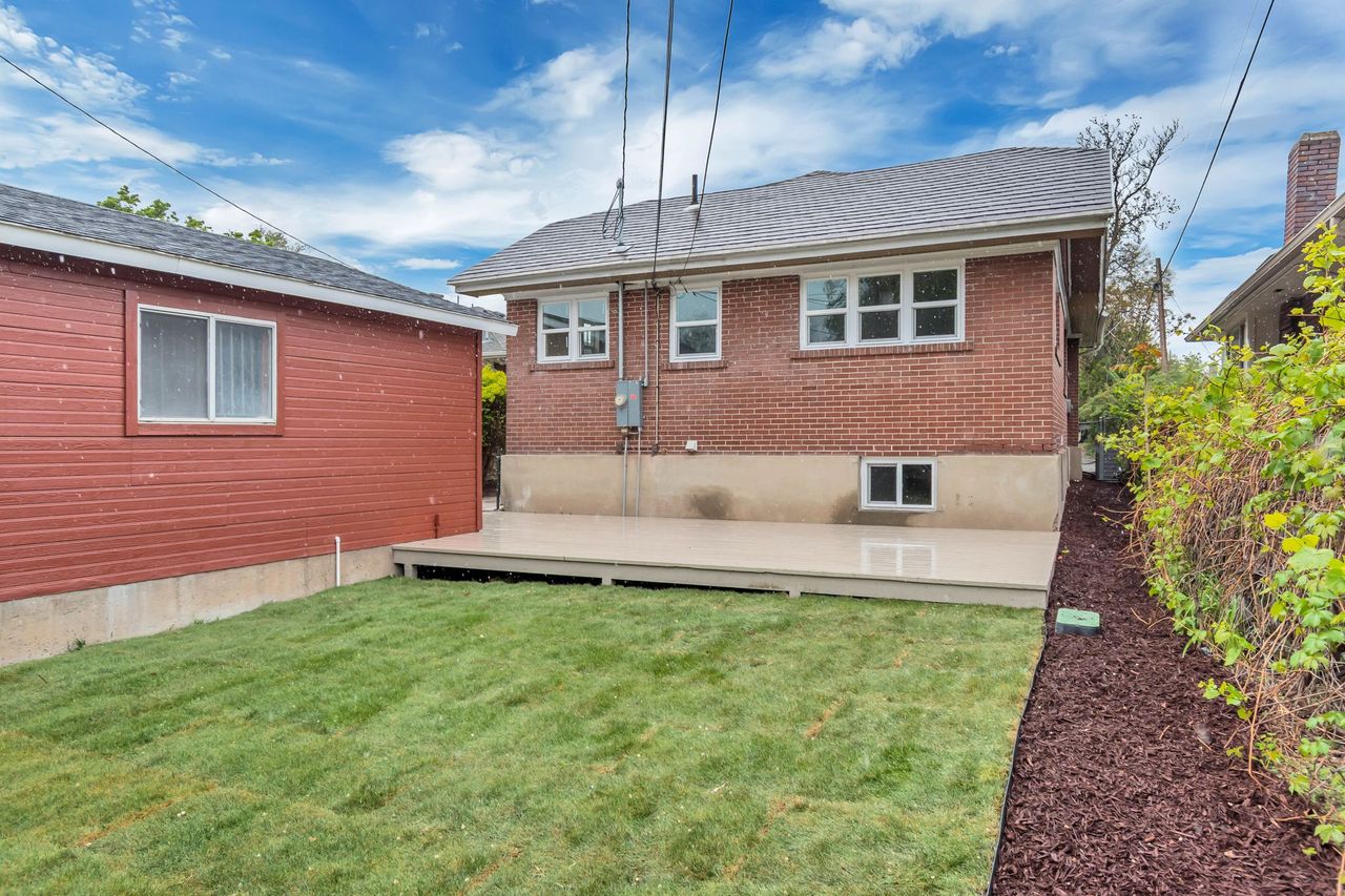 Back of property featuring a wooden deck, a yard, and brick siding