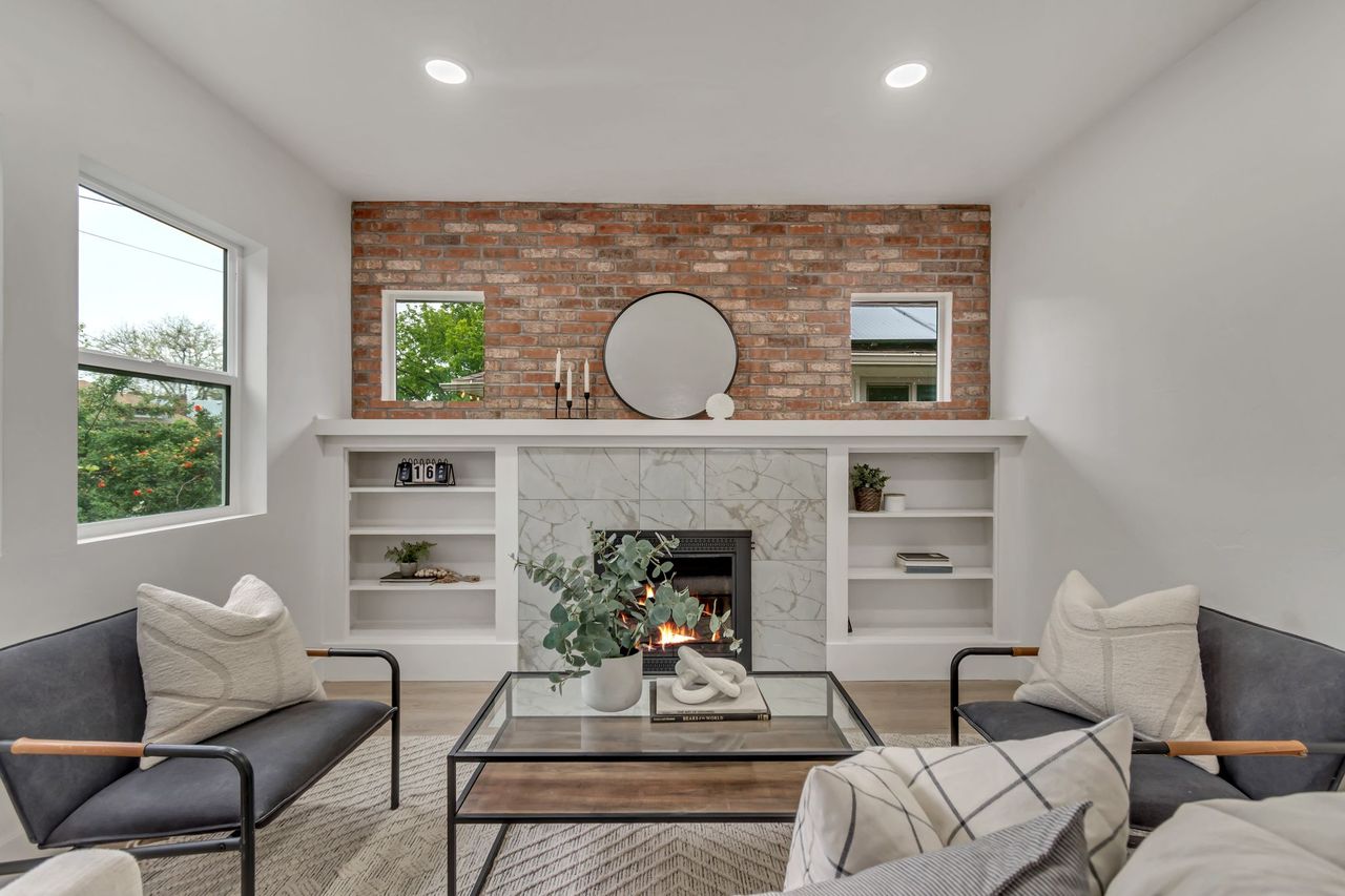 Living area featuring wood finished floors, a large fireplace, recessed lighting, brick wall, and built in shelves