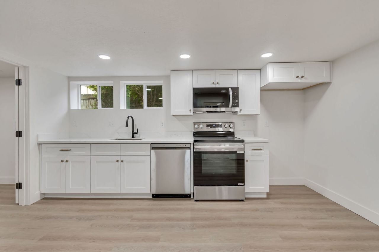 Kitchen with white cabinetry, stainless steel appliances, recessed lighting, and light wood-style floors