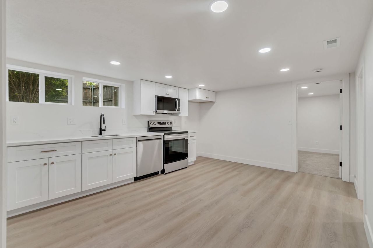 Kitchen with stainless steel appliances, recessed lighting, white cabinets, and light wood-style floors
