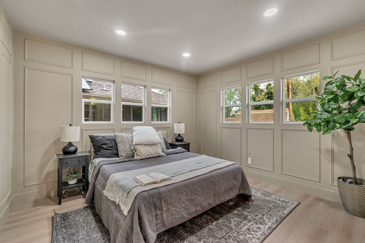 Bedroom with a decorative wall, light wood finished floors, and recessed lighting