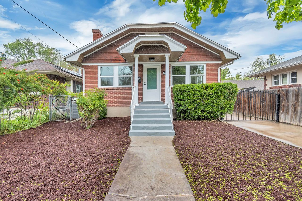 Bungalow-style house featuring a gate, a chimney, and brick siding