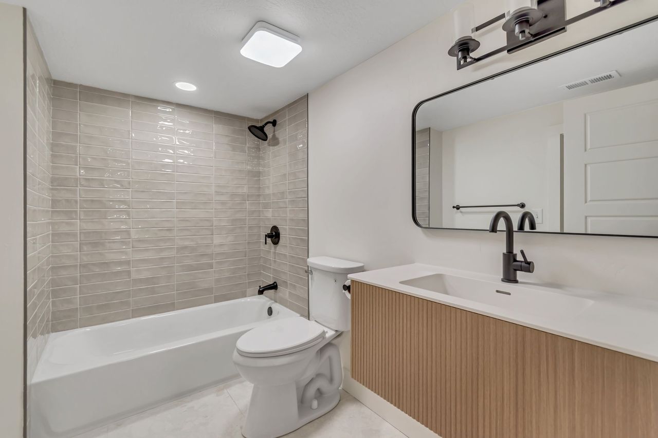 Bathroom with vanity, bathtub / shower combination, light tile patterned floors, and recessed lighting