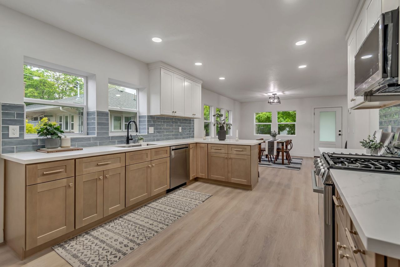 Dual tone kitchen with stainless steel appliances, decorative backsplash, plenty of natural light, recessed lighting, and a peninsula