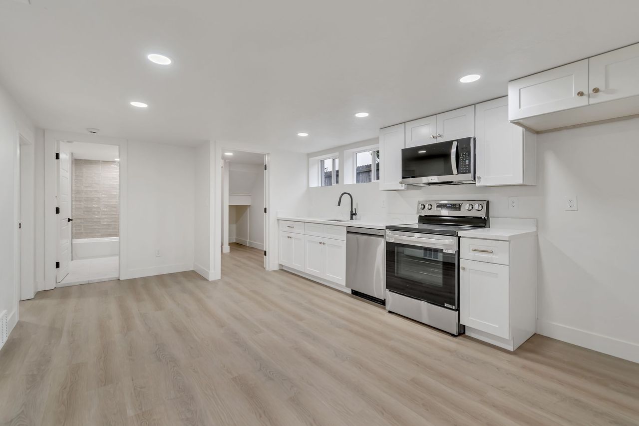 Kitchen with stainless steel appliances, white cabinetry, light countertops, recessed lighting, and light wood-style floors