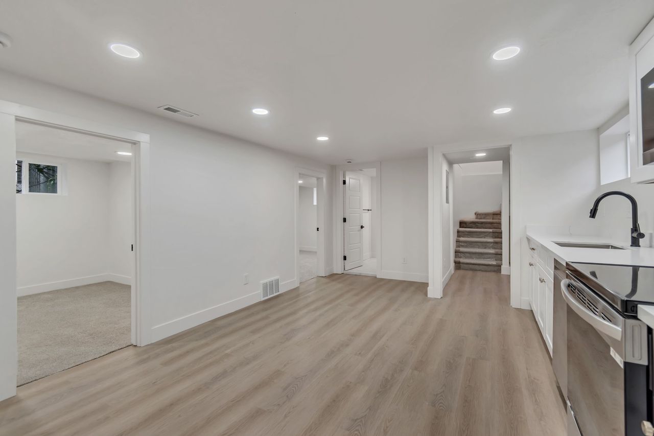 Kitchen with white cabinetry, recessed lighting, light wood finished floors, stainless steel range with electric cooktop, and glass fronted cabinets