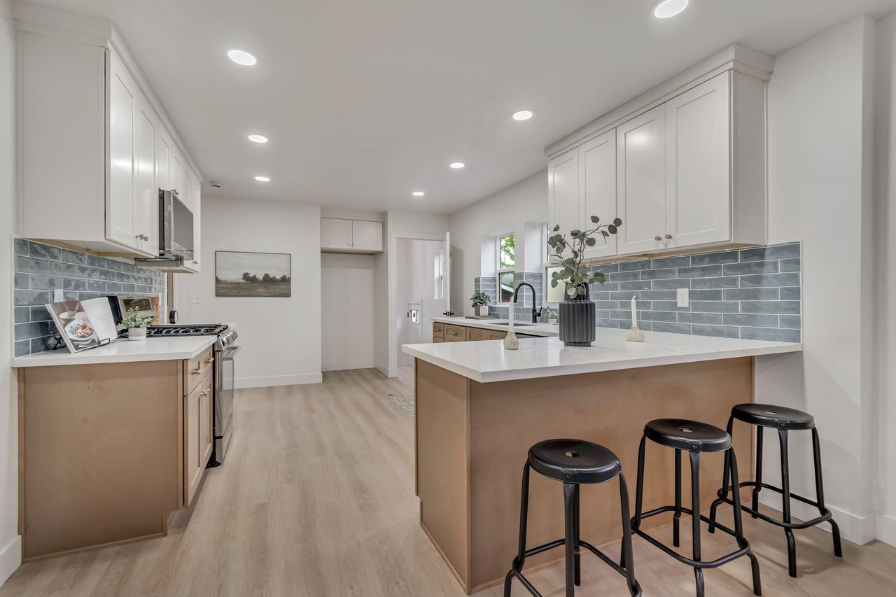 Kitchen with tasteful backsplash, a breakfast bar, stainless steel appliances, a peninsula, and light wood-style floors