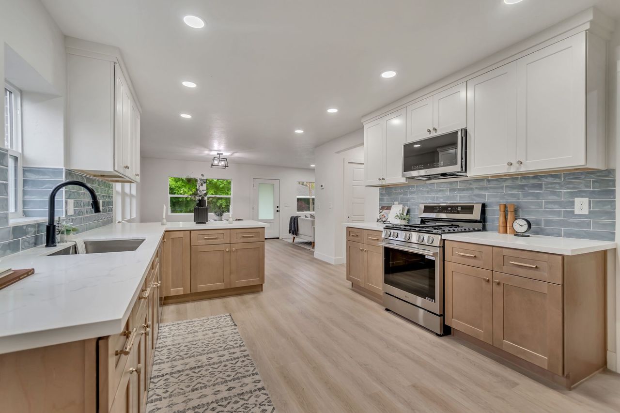 Dual tone kitchen featuring backsplash, stainless steel appliances, light wood-type flooring, recessed lighting, and a peninsula