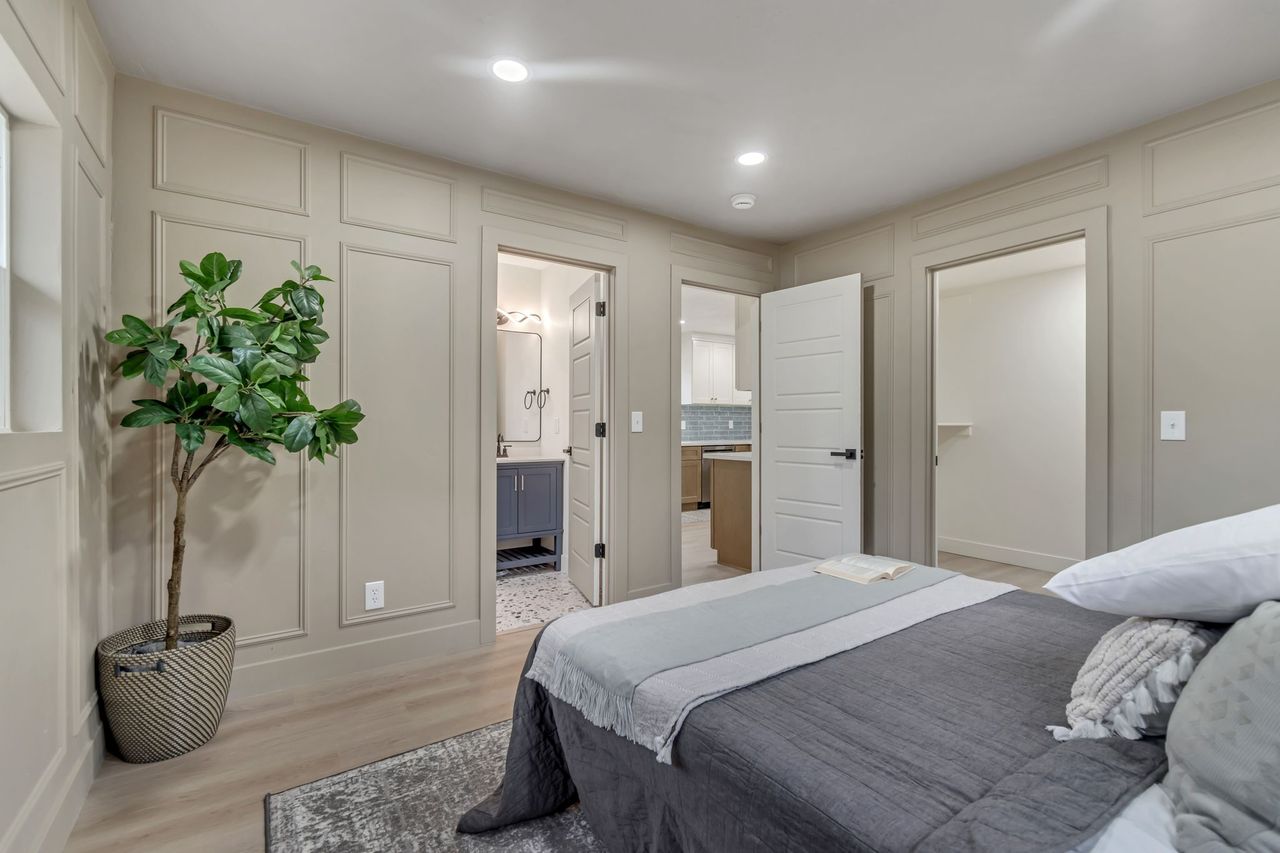 Bedroom featuring a decorative wall, light wood finished floors, recessed lighting, and connected bathroom