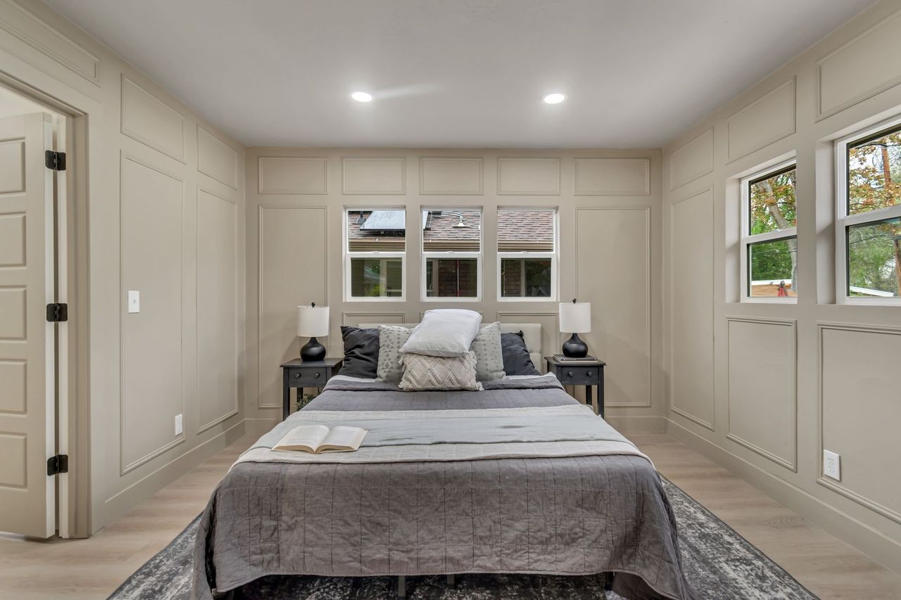 Bedroom with a decorative wall, light wood-style floors, and recessed lighting