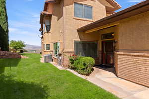 View of exterior entry featuring a yard, stucco siding, brick siding, and a mountain view