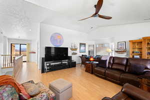 Living area with light wood-style flooring, ceiling fan, and plenty of natural light
