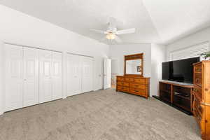 Carpeted bedroom featuring multiple closets and ceiling fan