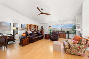 Living area with lofted ceiling, light wood-style floors, and a ceiling fan