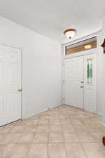 Entrance foyer featuring a textured ceiling and light tile patterned floors
