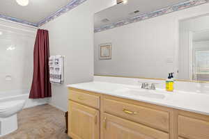 Full bath with vanity, shower / tub combo, and a textured ceiling