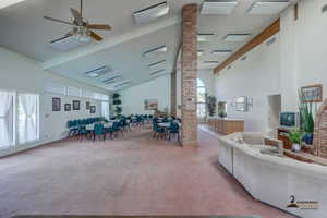 Carpeted living room featuring a ceiling fan and lofted ceiling