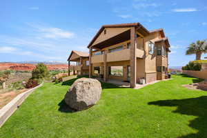 Back of house featuring stucco siding, a balcony, a yard, a patio area, and a mountain view