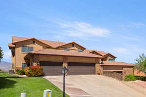 View of front of home featuring a garage, driveway, a tile roof, stucco siding, and a front lawn