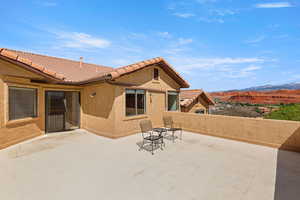 Rear view of property with stucco siding, a mountain view, a patio, and a tile roof