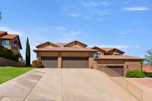 View of front of property with a tiled roof, driveway, a garage, brick siding, and stucco siding