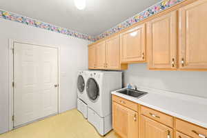 Laundry area with light floors, cabinet space, a textured ceiling, and washer and dryer