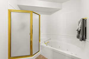 Full bathroom featuring a stall shower and a tub with jets