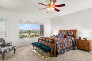 Bedroom with light colored carpet, a mountain view, and ceiling fan