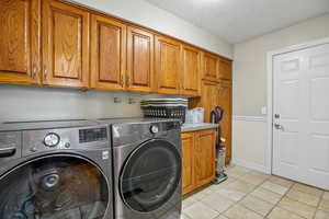 Laundry area with cabinet space, washer and clothes dryer, and a textured ceiling