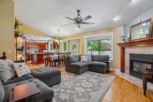 Living room with light wood-style floors, a fireplace, a chandelier, and a ceiling fan