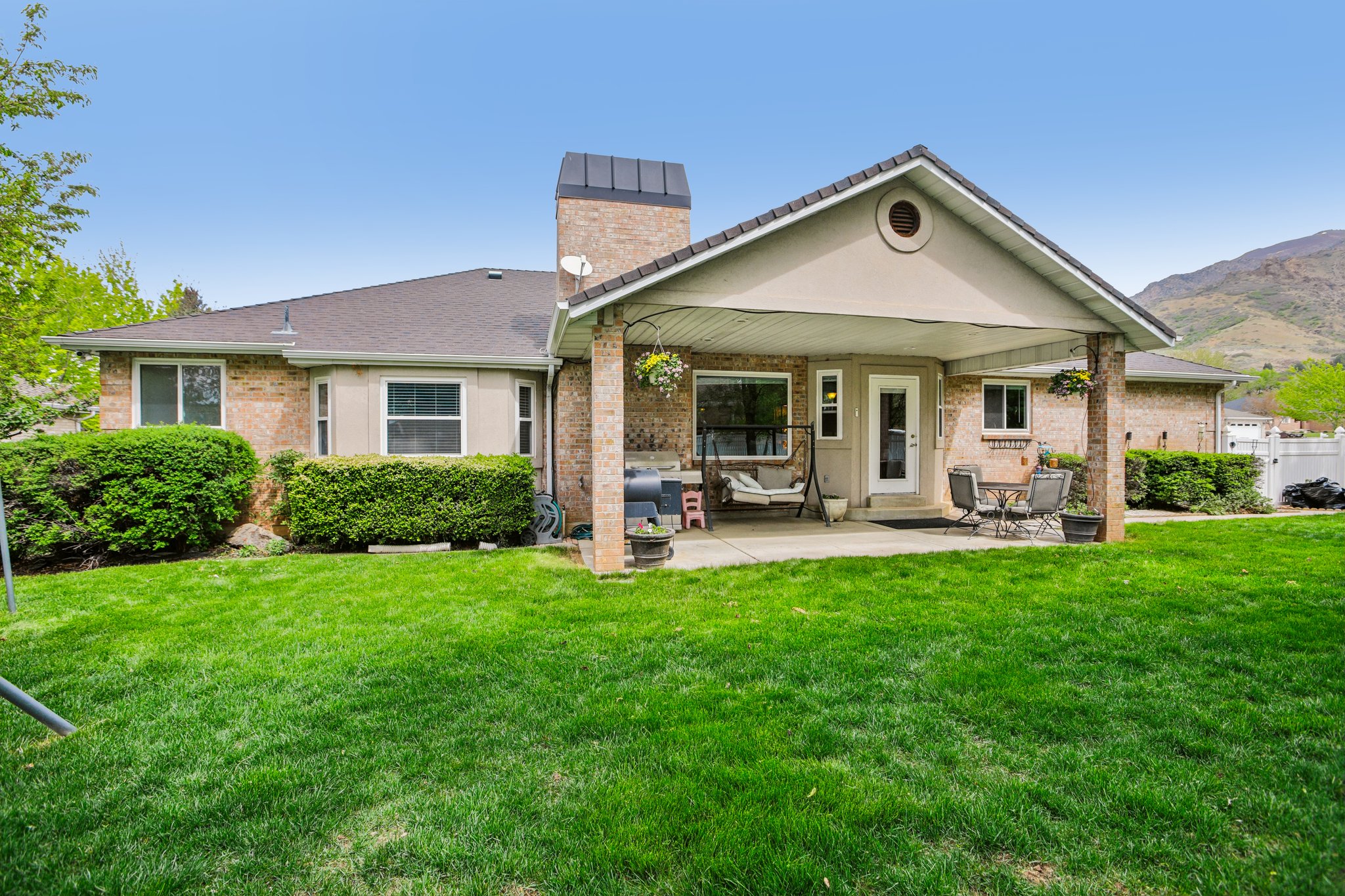 Rear view of house with a patio area, brick siding, a chimney, and a mountain view