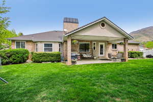 Rear view of house with a patio area, brick siding, a chimney, and a mountain view