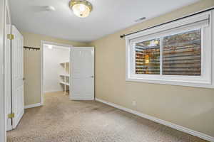 Unfurnished bedroom with a spacious closet, light carpet, and a textured ceiling