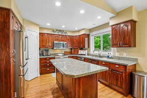 Kitchen with stainless steel appliances, light wood-style flooring, recessed lighting, and a center island