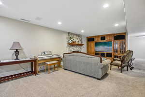 Living room featuring light colored carpet, a stone fireplace, and recessed lighting