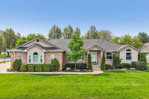 Single story home with brick siding, a front lawn, a shingled roof, and stucco siding