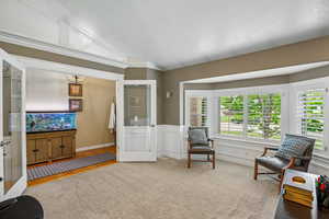 Sitting room featuring wainscoting, carpet, and a decorative wall
