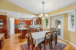 Dining space featuring lofted ceiling, suspended lighting, and light wood finished floors