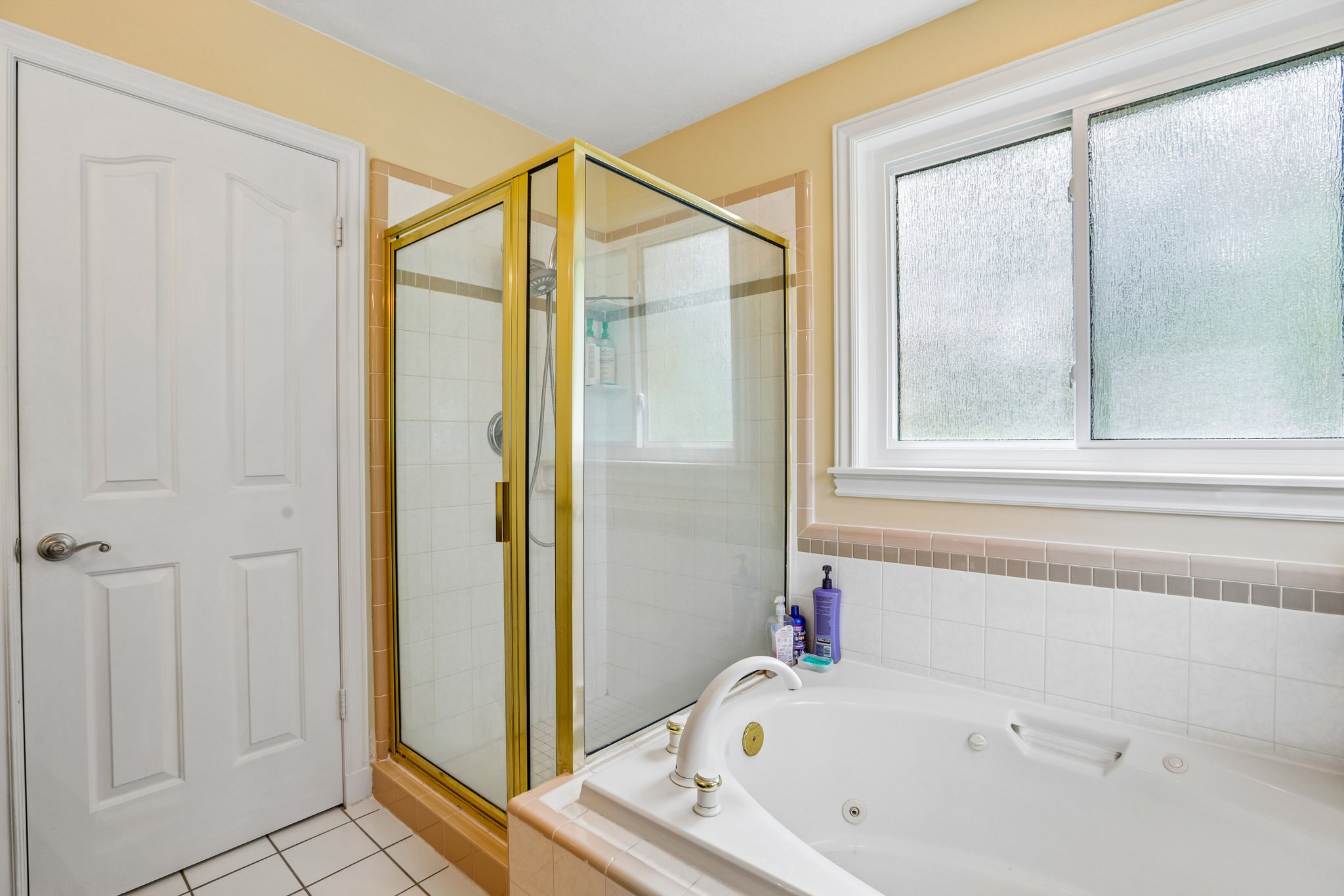 Bathroom with a jetted tub, a stall shower, and light tile patterned flooring