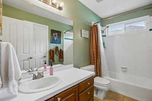 Bathroom featuring vanity, shower / bathtub combination with curtain, and light tile patterned floors