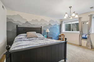 Bedroom with suspended lighting, light carpet, and a textured ceiling
