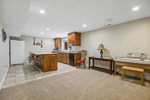 Kitchen featuring wood finish cabinetry, light countertops, freestanding refrigerator, recessed lighting, and a center island