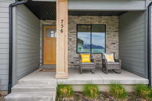 Doorway to property featuring stone siding and covered porch