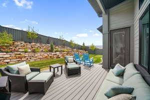 Wooden terrace with an outdoor hangout area and a fenced backyard