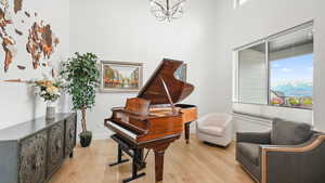 Sitting room featuring suspended lighting, light wood finished floors, and a high ceiling