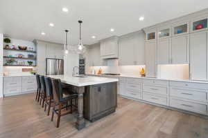 Kitchen featuring a breakfast bar area, stainless steel appliances, light wood-style floors, two tone color scheme, and an island with sink