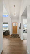 Entryway with suspended lighting, wood finished floors, and lofted ceiling