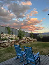Deck at dusk featuring a fenced backyard