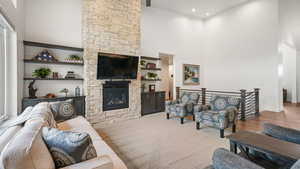 Living room featuring a high ceiling, a stone fireplace, and recessed lighting